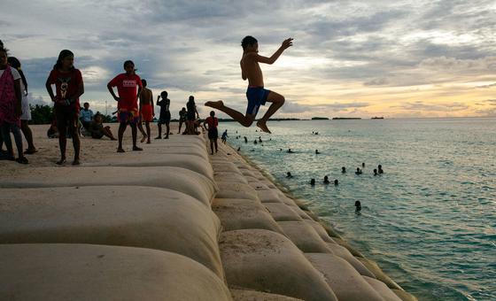 Des enfants de l'île de Tuvalu, dans l'océan Pacifique, jouent dans une zone côtière protégée par des sacs de sable.