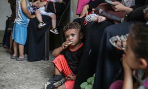 Children eat high-energy biscuits at a nutrition screening clinic in Gaza.