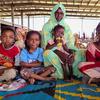 Watoto waliokimbia makazi yao na mwanamke wakiwa wameketi kwenye mkeka wenye rangi nyingi katika jengo ambalo halijakamilika huko Minah Al Berih, jimbo la Gedaref, Sudan, Julai 10, 2024.