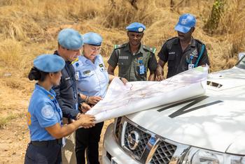 Police Commissioner Christine Fossen, UNMISS, leads a team of uniformed women peacekeepers in South Sudan, reviewing a map over the hood of a vehicle.