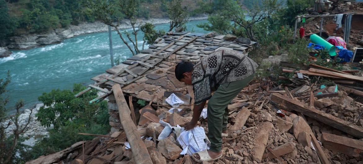 एक लड़का रुकुम में भूकम्प में ध्वस्त हुए अपने घर के मलबे पर बैठा है.