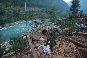 Um menino vasculha os escombros de sua casa atingida pelo terremoto em Rukum West, Nepal