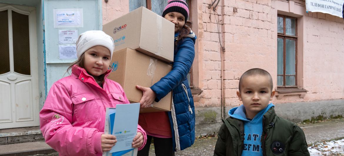 A family receives winter clothing kits for children and other supplies from UNICEF in the frontline community of Marhanets, in the east of Ukraine.