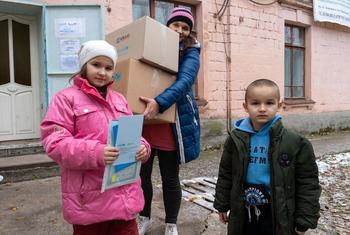 Una familia recibe kits de ropa de invierno para niños y otros suministros de UNICEF en la comunidad de primera línea de Marhanets, en el este de Ucrania.