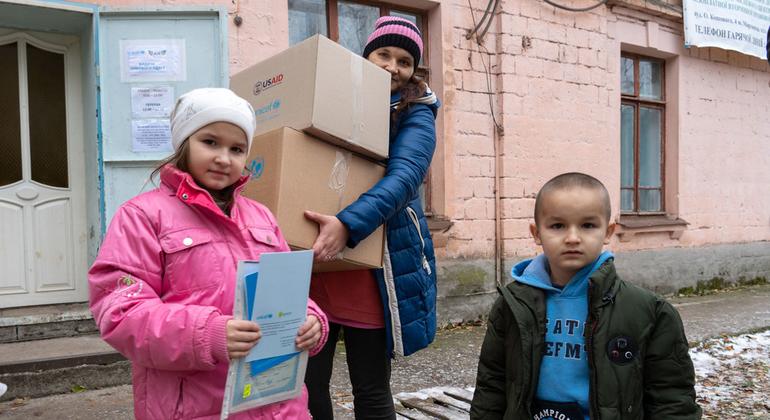 Una familia recibe kits de ropa de invierno para niños y otros suministros de UNICEF en la comunidad de primera línea de Marhanets, en el este de Ucrania.