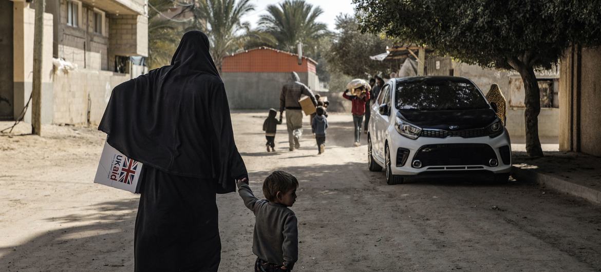 A woman carries children's winter clothes in Der Al Balah Gaza.