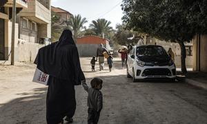 A woman carries children's winter clothes in Der Al Balah Gaza.