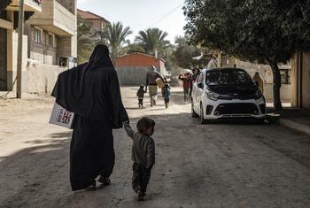 A woman carries children's winter clothes in Der Al Balah Gaza.