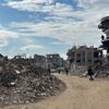 Détruction à Jabalya, dans le nord de Gaza, avec des gens marchant dans des rues dévastées et des bâtiments endommagés sous un ciel partiellement nuageux.