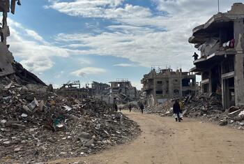 Détruction à Jabalya, dans le nord de Gaza, avec des gens marchant dans des rues dévastées et des bâtiments endommagés sous un ciel partiellement nuageux.