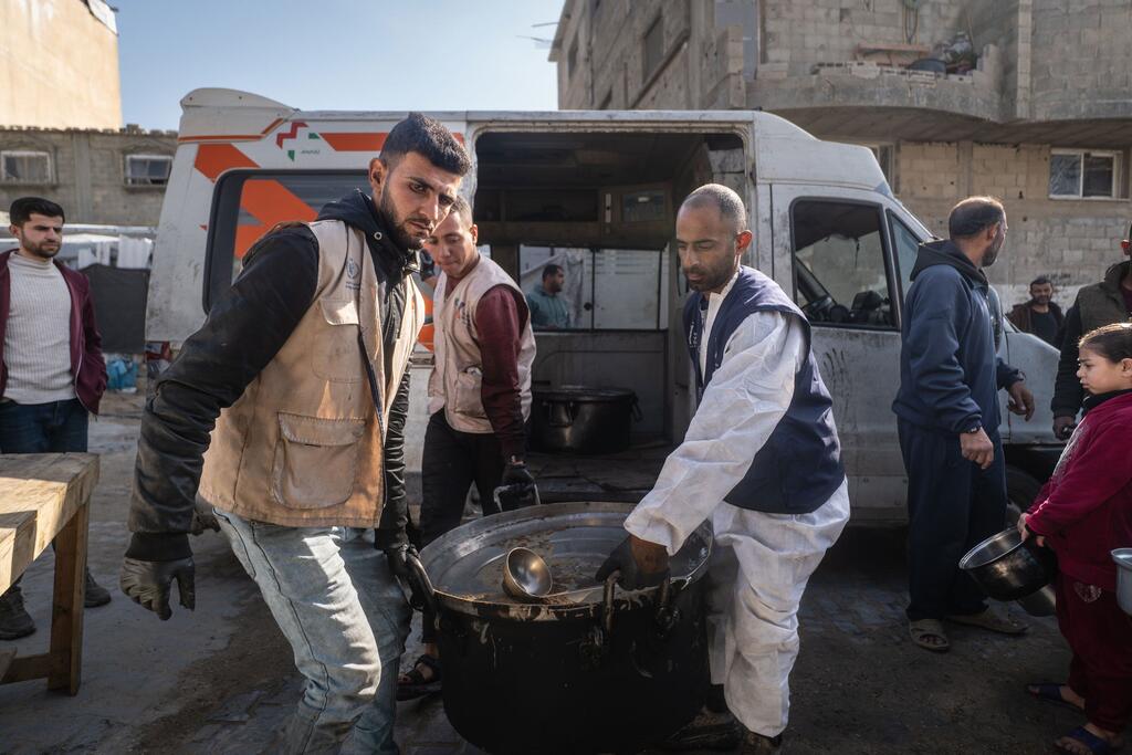 Les travailleurs d'une cuisine de repas chauds soutenue par le PAM distribuent de la nourriture à Khan Younis, à Gaza. La cuisine prépare plus de 11 000 repas quotidiens pour les familles touchées par la guerre, continuant de servir la communauté.