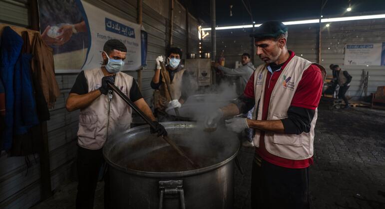 Abu Muhammad, head chef at a WFP-supported hot meals kitchen in Khan Younis, inspects food prepared by his colleagues while helping to serve over 11,000 daily meals to war-affected families in Gaza.