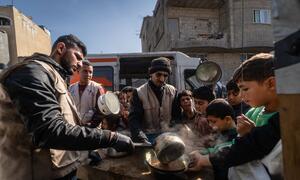 Workers of a WFP-supported hot meals kitchen distribute food in Khan Younis, Gaza. The kitchen prepares over 11,000 daily meals for families affected by the war, continuing to serve the community.