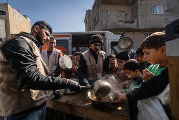 Workers of a WFP-supported hot meals kitchen distribute food in Khan Younis, Gaza. The kitchen prepares over 11,000 daily meals for families affected by the war, continuing to serve the community.