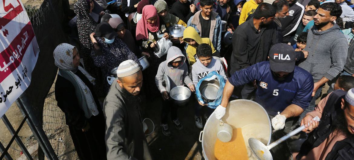 Gazatíes hacen cola para conseguir alimentos.
