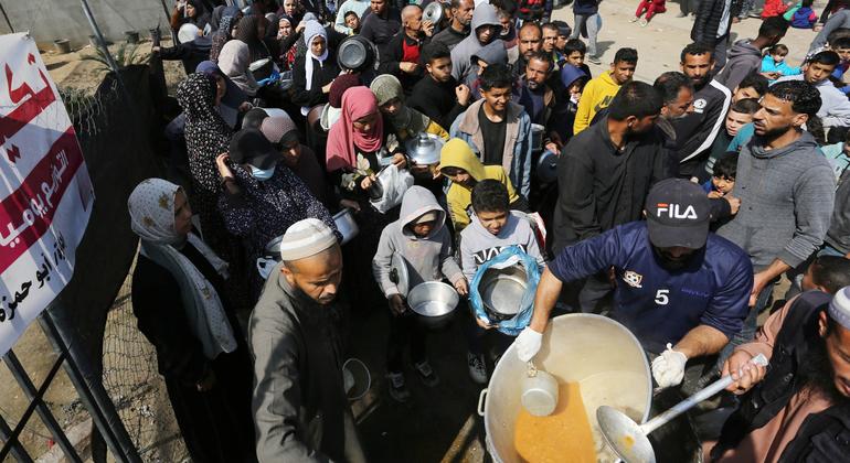 Gazatíes hacen cola para conseguir alimentos.