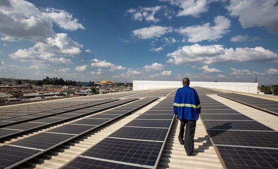 A technician  checks solar panels on the roof of the Medical Stores Limited warehouse in downtown Lusaka, Zambia.