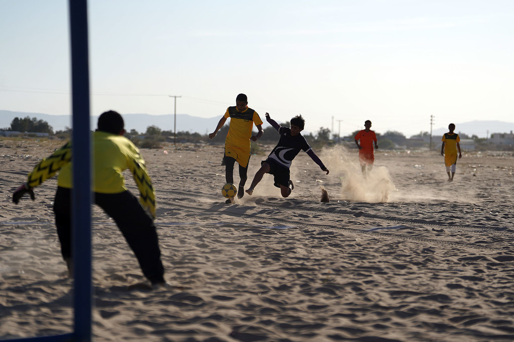 En Ma'rib, los jóvenes jugadores practican fútbol en un campo polvoriento, pateando el balón y corriendo por la arena.