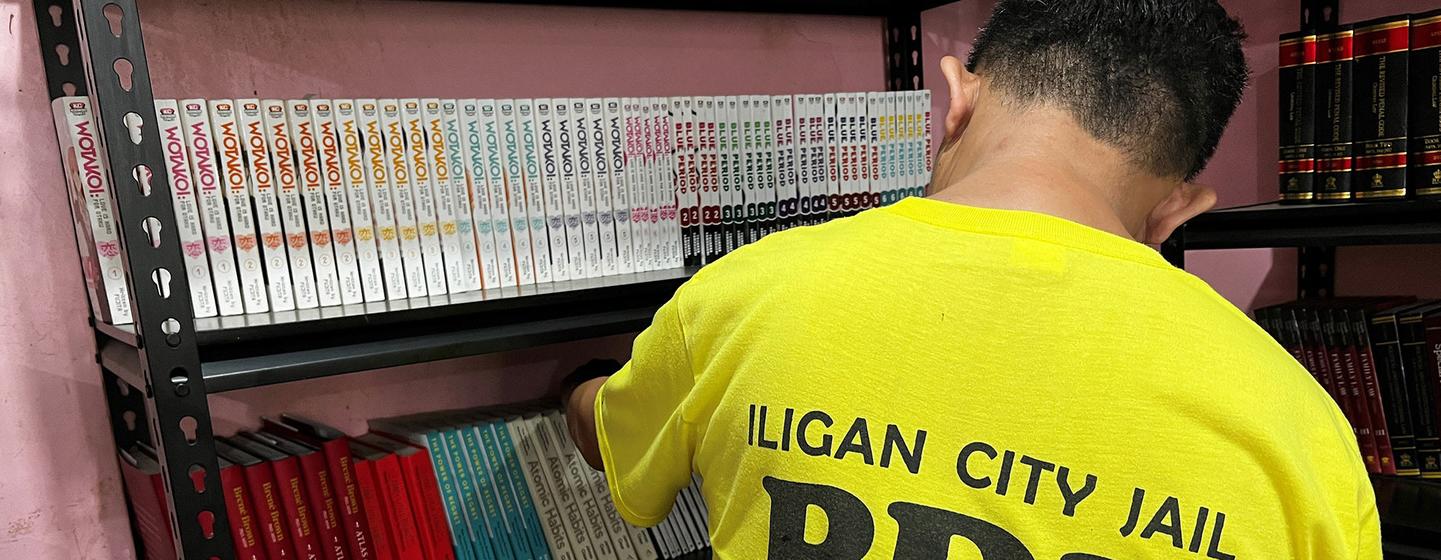 A prisoner arranges books in the library at Iligan City Jail.