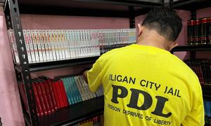 A prisoner arranges books in the library at Iligan City Jail.