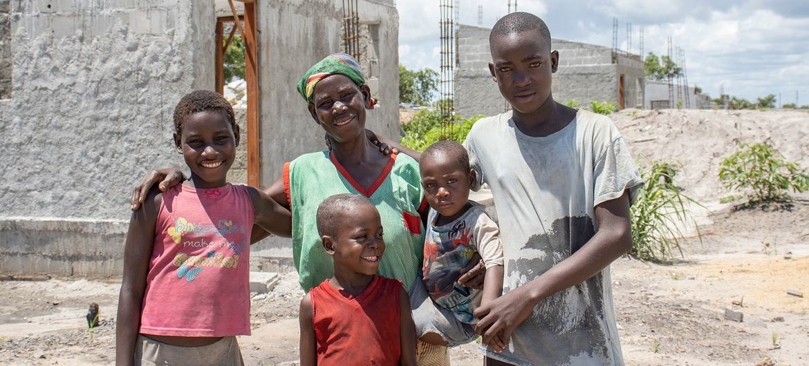 Cecília Valentim, standing with four of her seven children in front of her new resilient house under construction in Mandruzi resettlement camp in the Dondo district, Sofala province, Mozambique, was among 1.8 million people needing humanitarian assistan…