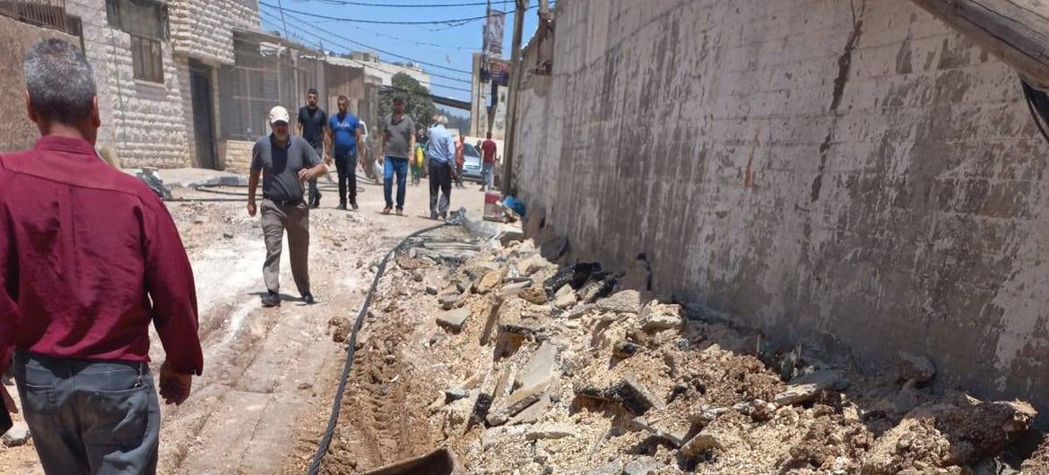 Pessoas passam por infraestrutura de esgoto e água na cidade de Jenin, na Cisjordânia, que foi destruída após a operação militar israelense de dois dias.
