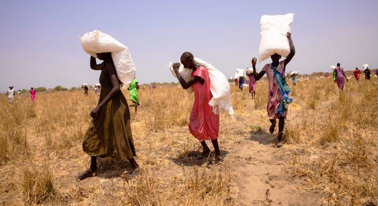 سيدات من جنوب السودان يحملن أكياس الحبوب بعد إسقاطها جواً خارج بييري في ولاية جونقلي.