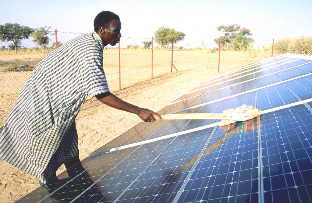 Un homme nettoie un panneau solaire au Niger.