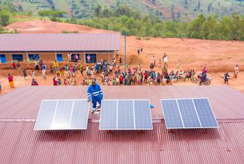 Un technicien installe des panneaux solaires sur un centre de santé au Burundi.