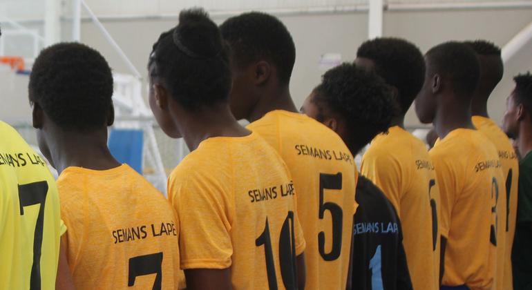 Un grupo de mujeres y hombres jóvenes haitianos participan en un evento deportivo en Puerto Príncipe.