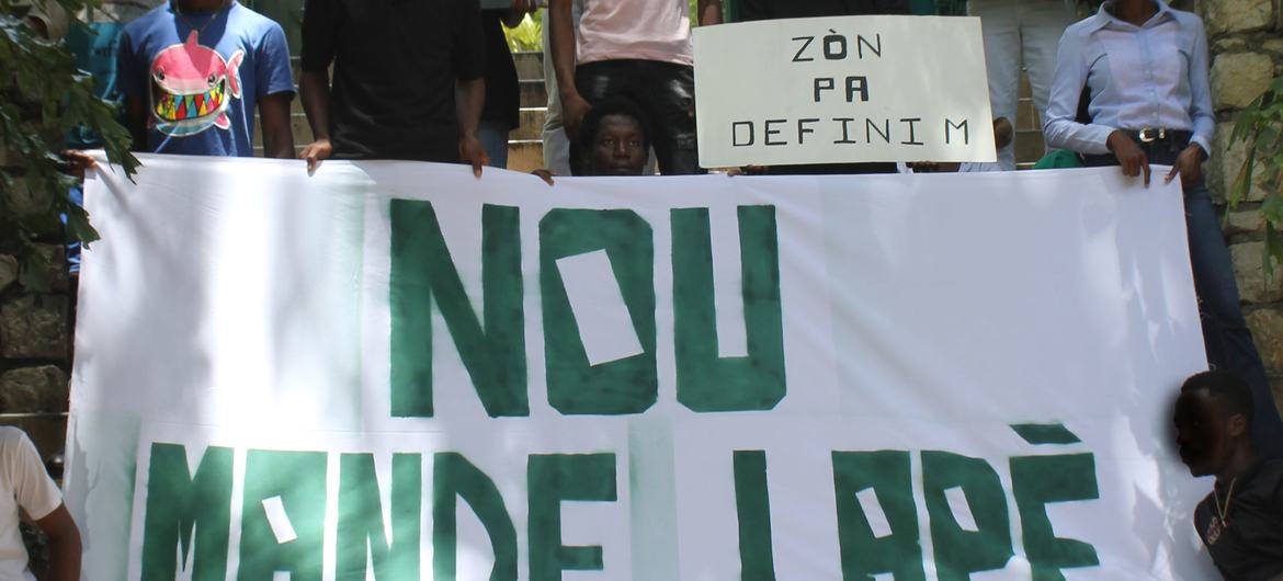 Une banderole tenue par des jeunes sur laquelle est écrit : "Nous demandons la paix".