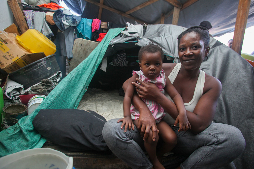 Une mère tient sa fille dans ses bras dans un abri de fortune installé dans une école après avoir fui les attaques des groupes armés à Port-au-Prince.