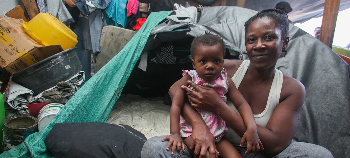 A mother holds her daughter at a makeshift shelter in a school after fleeing attacks by armed groups in Port-au-Prince.