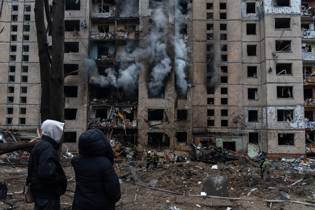 Les gens regardent un bâtiment brûler à Kiev suite à une attaque de missile.