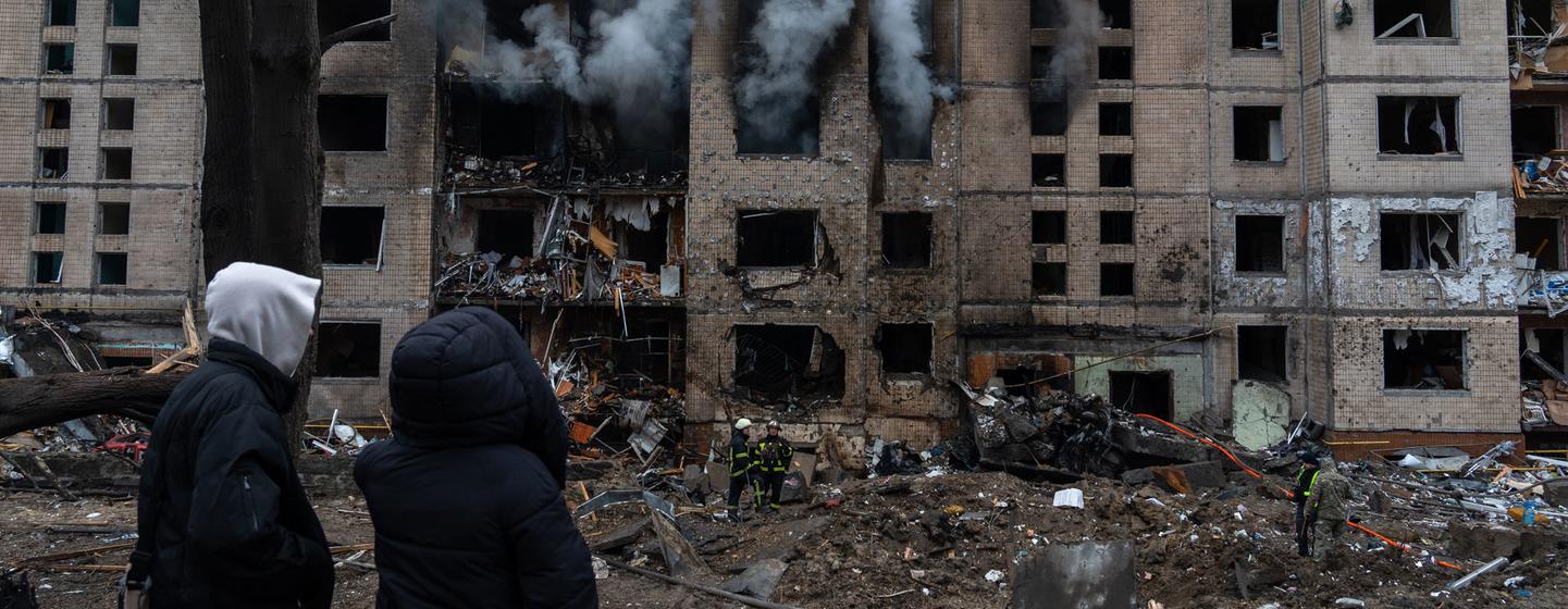 People watch on as a building burns in Kyiv following a missile attack.