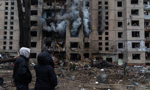 People watch on as a building burns in Kyiv following a missile attack.