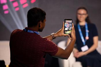 A man takes a photo of a speaker at the AI for Good Summit in Geneva.