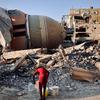 A person collects water in the midst of the ruins of Gaza.