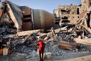 A person collects water in the midst of the ruins of Gaza.