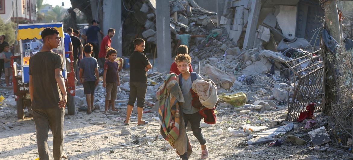 A boy carries possessions from a bombed out building in Gaza.