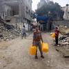 Niños buscando agua en un barrio bombardeado en Gaza.