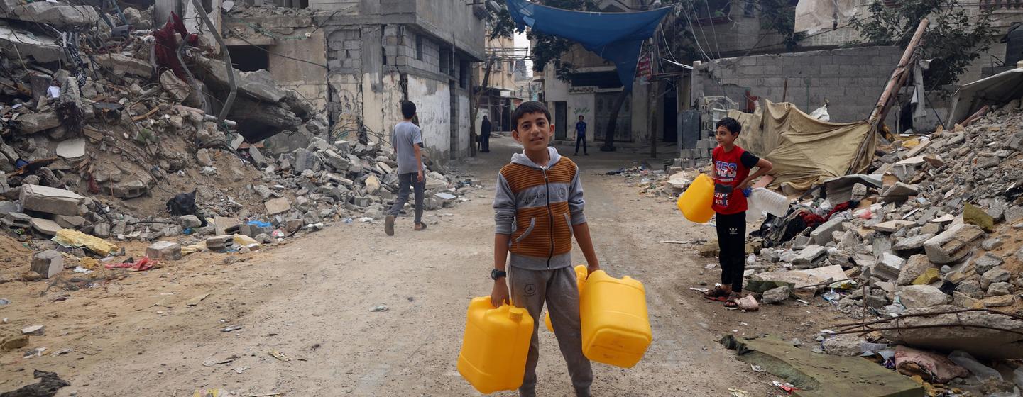 Un garçon va chercher de l’eau dans un quartier bombardé de Gaza.