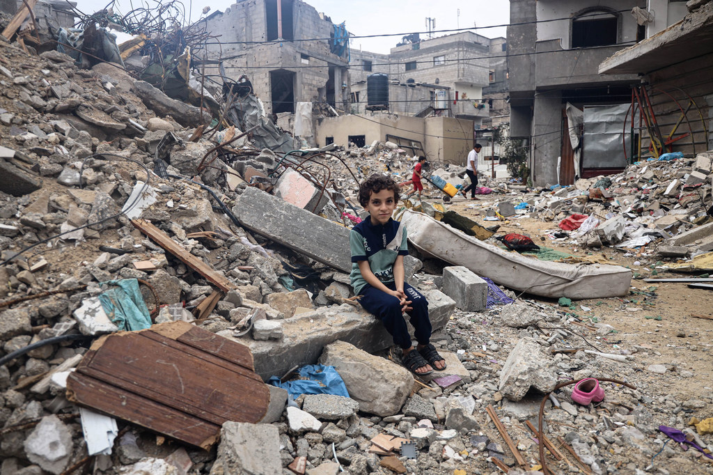 An 8-year-old boy from Rafah City, sits amongst the rubble of his family's destroyed home.