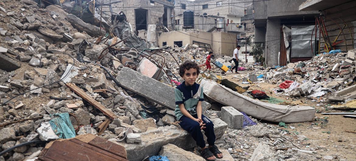 Um menino de 8 anos da cidade de Rafah está sentado entre os escombros da casa destruída de sua família