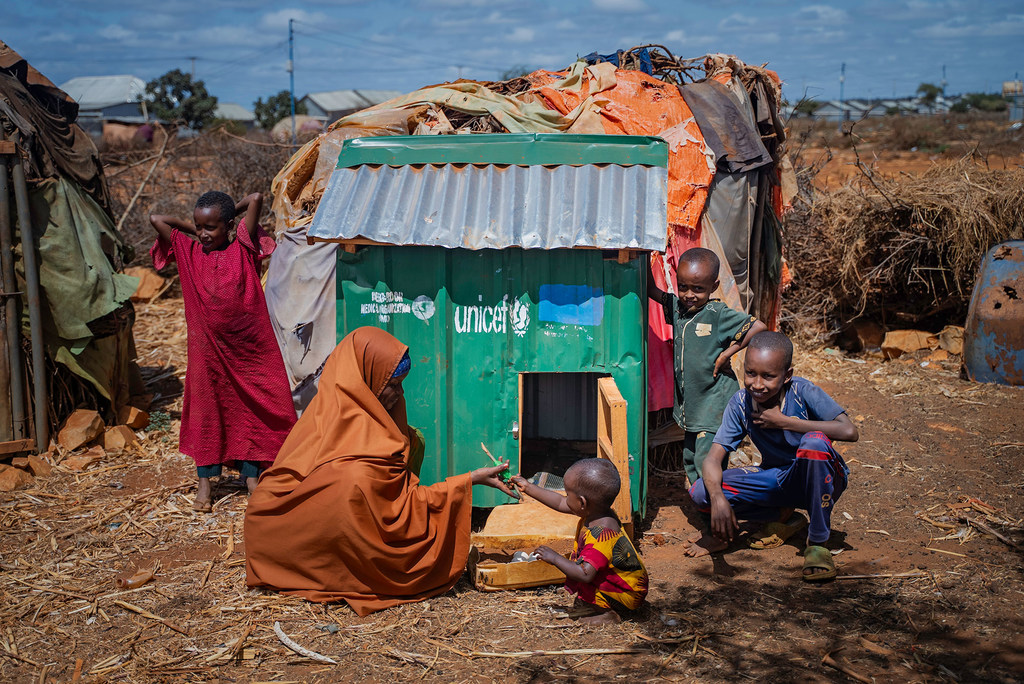 A family poses next to a chicken house provided by UNICEF, in Barwaaqo Camp, Baidoa, Somalia.
