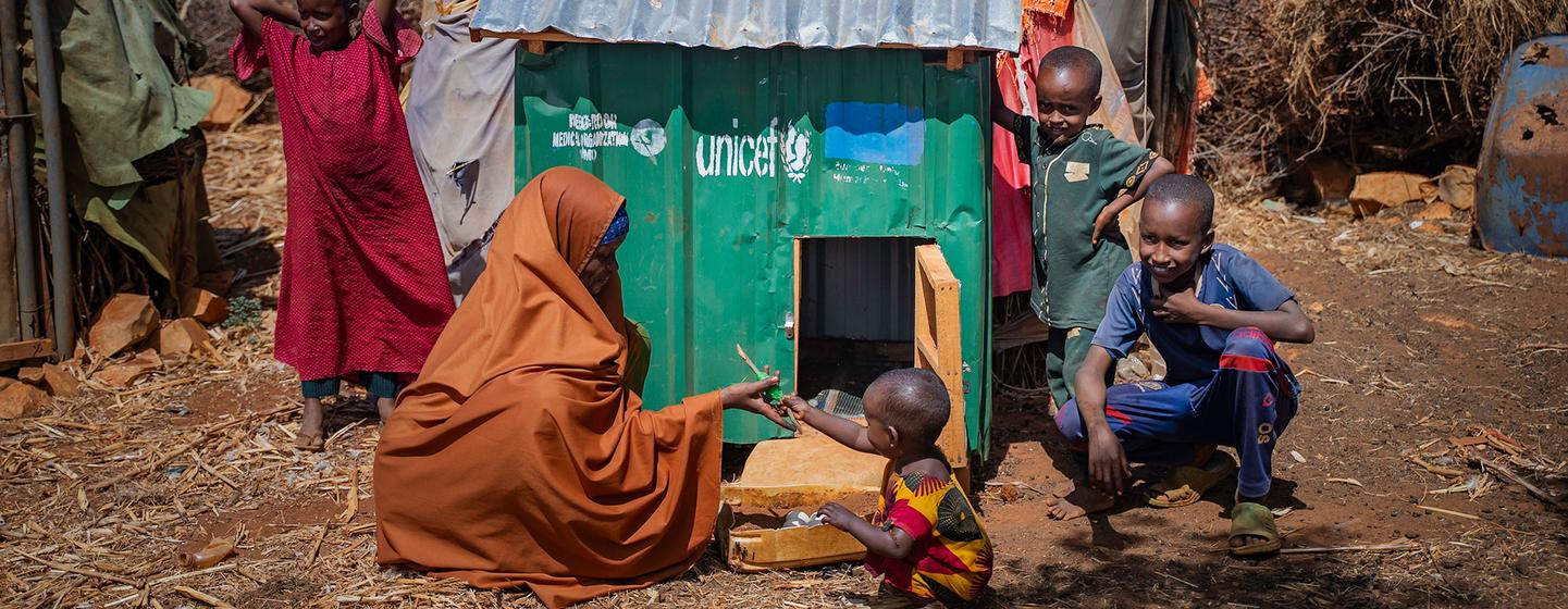 Une femme somalienne et ses enfants posent à côté d'un poulailler vert de l'UNICEF dans un camp de déplacés internes à Barwaaqo, à Baidoa, en Somalie.