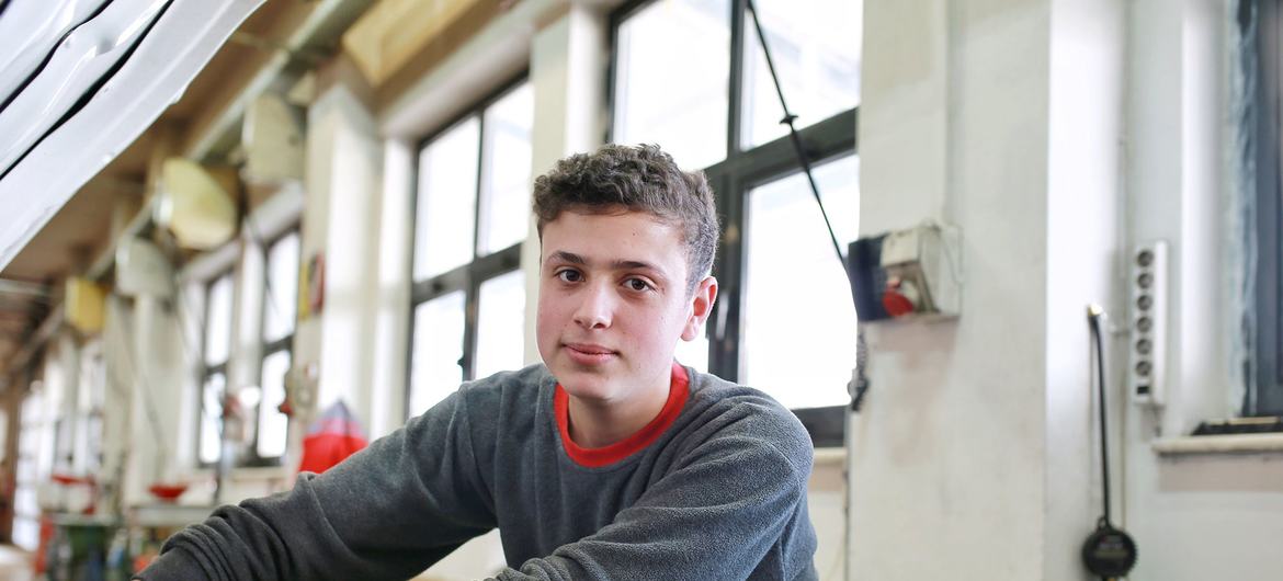 Young man named Alaaddin works on a car engine during an apprenticeship program in Konya.