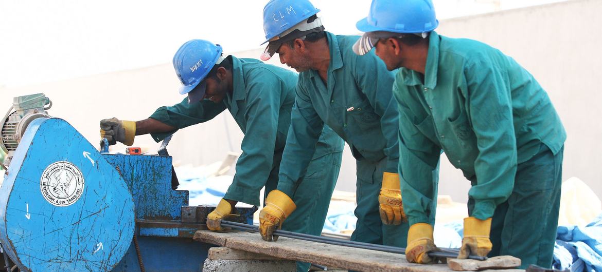 在阿联酋的一个建筑工地上，外国工人在切割钢材。