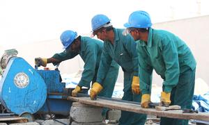 Trabajadores migrantes cortan acero en un sitio en construcción en los Emiratos Árabes.