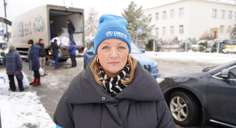 Элизабет Арнсдорф Хаслунд, одетая в шляпу УВКБ ООН, стоящая перед грузовиком во время раздачи зимней помощи в Украине.